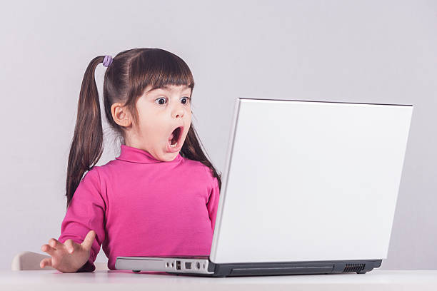mała dziewczynka reaguje podczas korzystania z laptopa - pigtails zdjęcia i obrazy z banku zdjęć