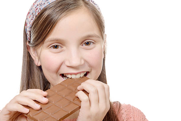 istock preteen  girl eats chocolate, isolated on white 515523770