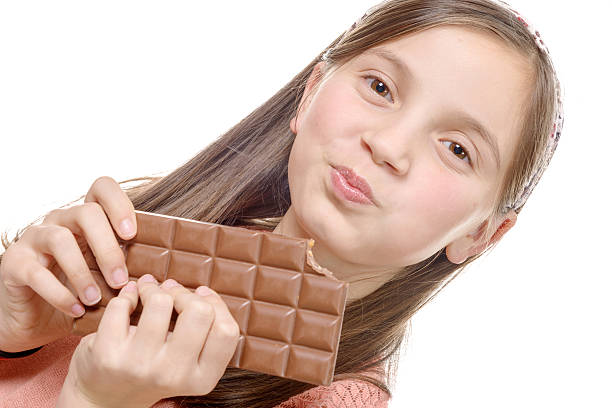 istock preteen  girl eats chocolate, isolated on white 515524076