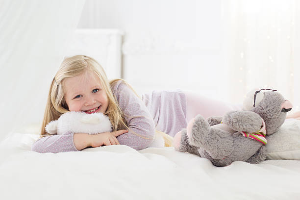 istock Child girl lying in bed with teddy bear 515525032