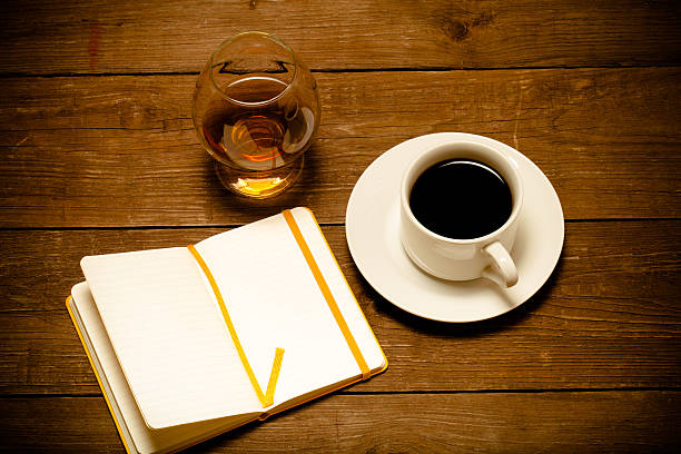 istock White cup of coffee, cognac in a glass and notebook 515530304