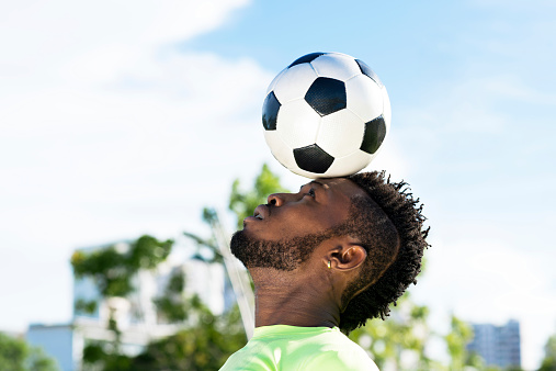 African-American player balancing soccer ball on his head
