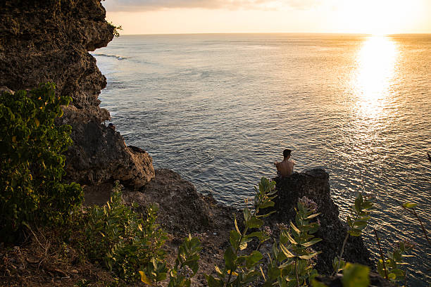 Balangan, Bali, Indonesia - August 9, 2014: Single person is looking the ocean at the sunset. To the south of Denpasar, in the peninsula of Kuta Seletan, is a seaside resort called Balangan. The bay is not as crowded as the other places on the Ocean and you can enjoy a wonderful view. 