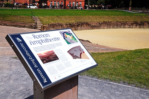 Chester, United Kingdom - July 22, 2014:  Roman Amphitheatre sign with the Roman Amphitheatre to the rear and tourists in the distance, Chester, Cheshire, England, UK, Western Europe.