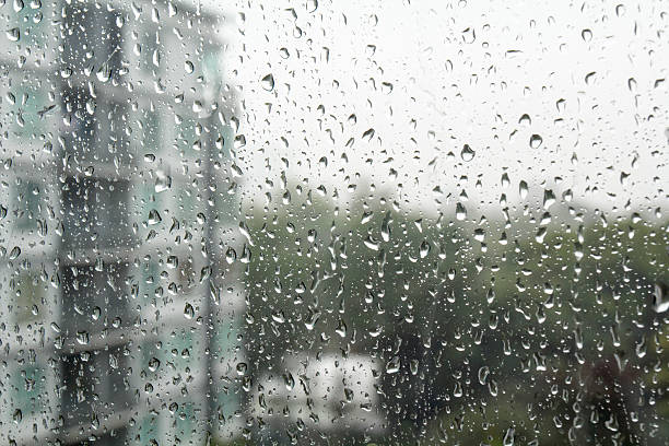 istock Drops of rain on a window pane, buildings in background. 515552723