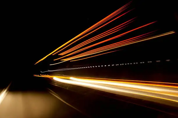 Night time highway blurred stream of light as trucks pass