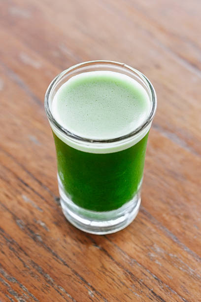 istock Shot glass of Wheatgrass drink on wood surface 515579281