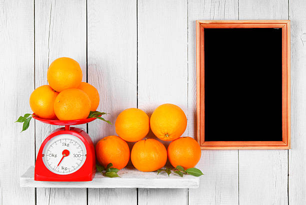 Orange on scales and in a basket on a wooden shelf. A framework on a wooden background.