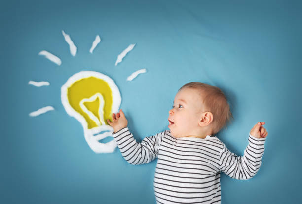 One year old boy with a bulb on blue background. Child with an idea