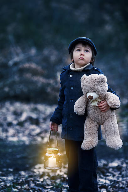 istock Cute little child, holding lantern and teddy bear in forest 515593976