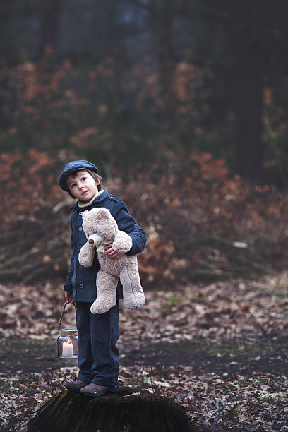 istock Cute little child, holding lantern and teddy bear in forest 515594048