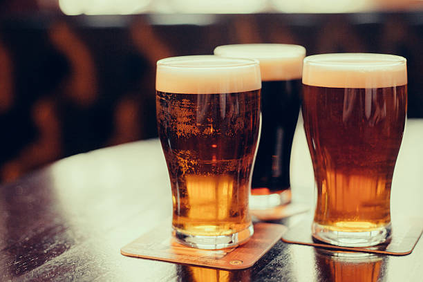 Glasses of light and dark beer on a pub background. Glasses of light and dark beer on a pub background. lager stock pictures, royalty-free photos & images