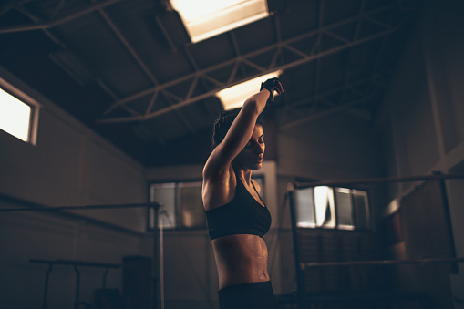 Photo of a young determined woman who is having her daily exercise in the gym.