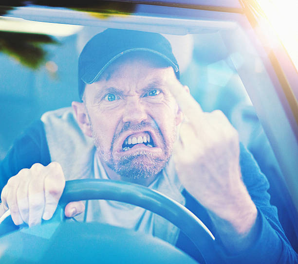 istock Road rage! Furious man makes obscene gesture through windscreen 515597868
