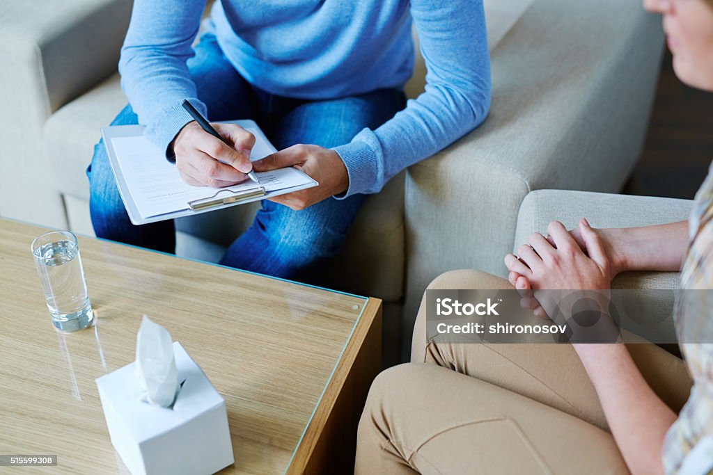Psychological therapy Male psychologist making notes during psychological therapy Psychotherapy Stock Photo