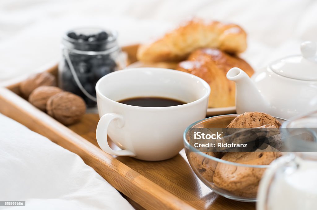 Early morning breakfast Breakfast in bed with hot coffee and croissants. Healthy breakfast kept on bed. Close up of a cup of tea with cookies on wooden tray in bed. Breakfast Stock Photo