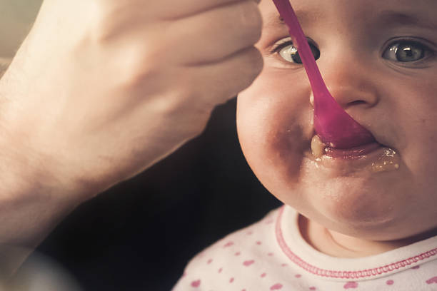 istock Feeding a baby girl with a spoon - messy 515601364