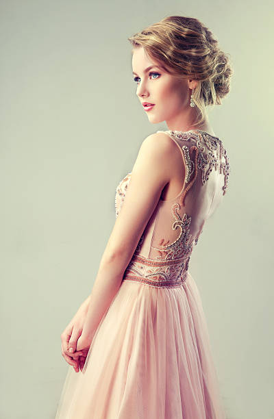 Beautiful girl light brown hair with an elegant hairstyle. Young beautiful woman, dressed in evening gown.Example of wedding hairstyle. pink gown stock pictures, royalty-free photos & images