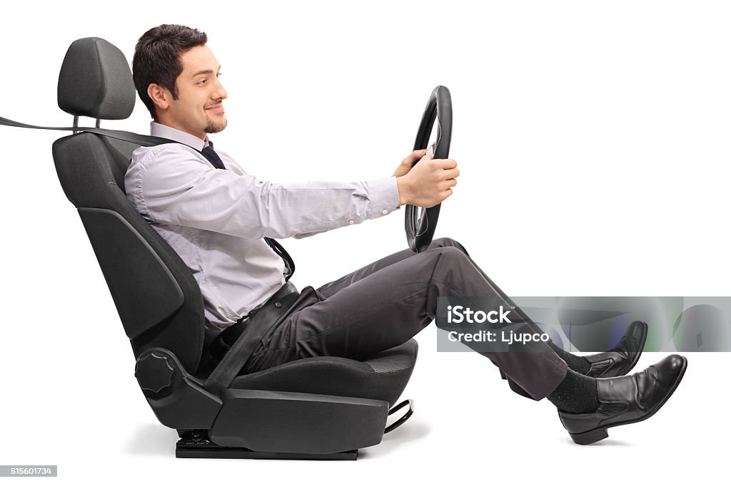 Man driving seated on a car seat Profile shot of a young man holding a steering wheel seated on a car seat isolated on white background Driving Stock Photo