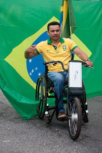 São Paulo, Brazil, March, 13, 2016: Demonstrator in a wheelchair in front of a flag of Brazil. About 2 million demonstrators on Paulista Avenue calling for an end to corruption in Brazilian politics and punishment of politicians and businessmen involved misuse of public money