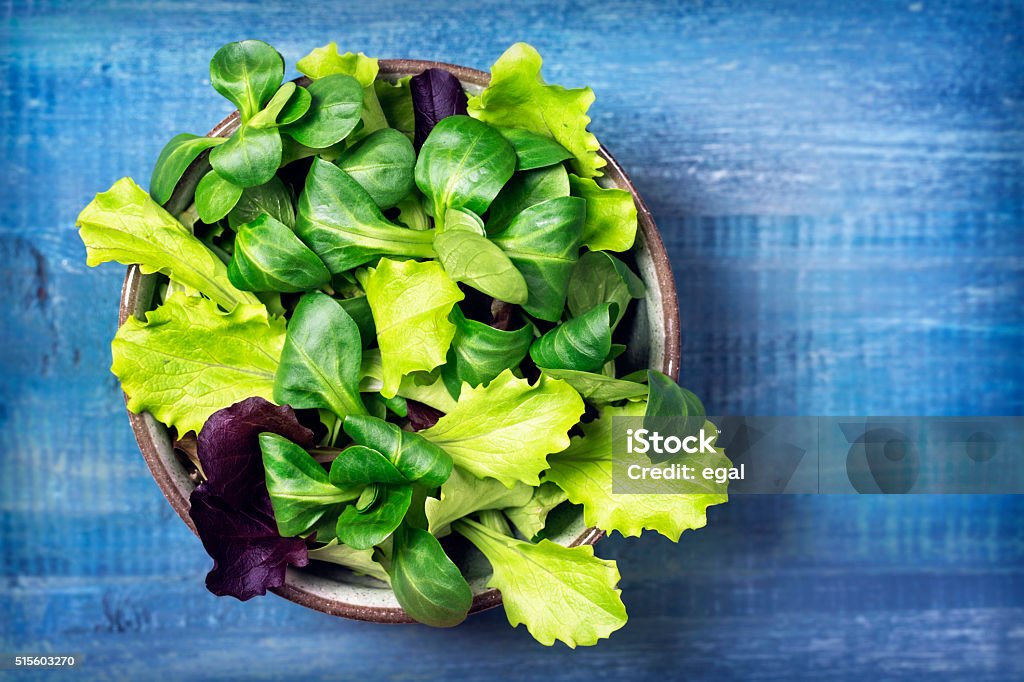 Mixed green salad leaves in a bowl Mixed green salad leaves in a bowl on a blue background Salad Stock Photo