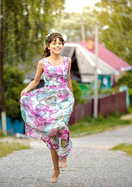 Young beautiful brunette woman running along a rural road at a summer day