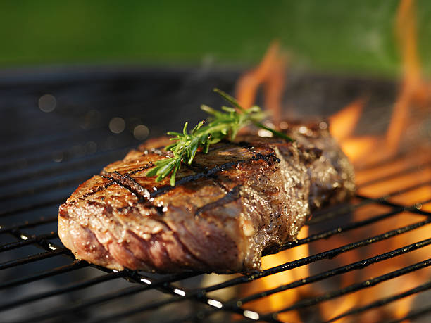 istock barbecueing teak with flames on grill 515628097