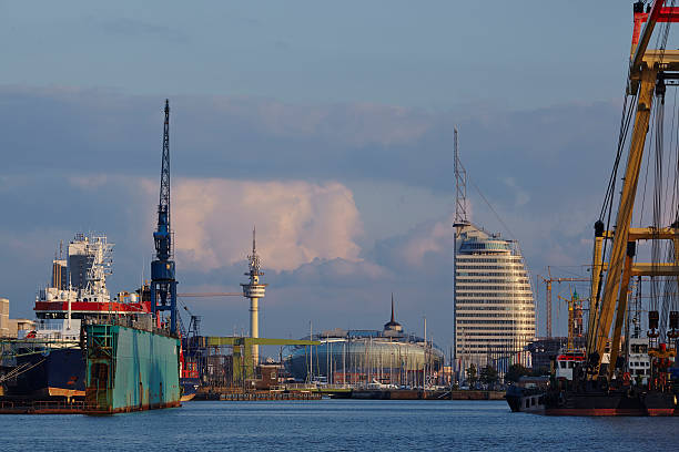 The inner city and skyline of Bremerhaven (Germany, federal state Bremen) taken from the harbour. In the foreground are some docks, ships, cranes and harbour installations.