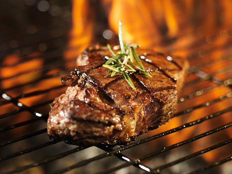 steak with flames on grill with rosemary shot close up with selective focus