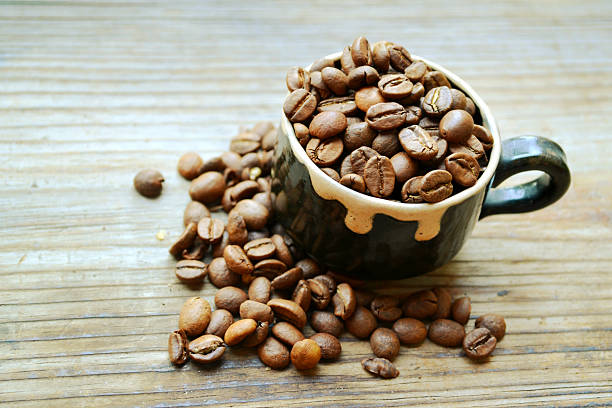 istock Cup full of coffee beans on wooden table 515631411