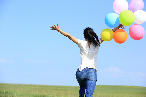 young asian woman  on green grassland with colored balloons