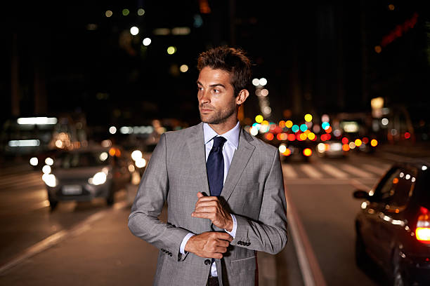 Suave in the city A handsome businessman posing in the middle of a busy city street at night man adjusting tie stock pictures, royalty-free photos & images
