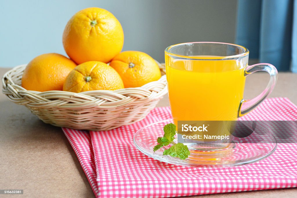 Orange juice and oranges in basket on wooden table. Close up orange juice and oranges in basket on wooden table. Basket Stock Photo