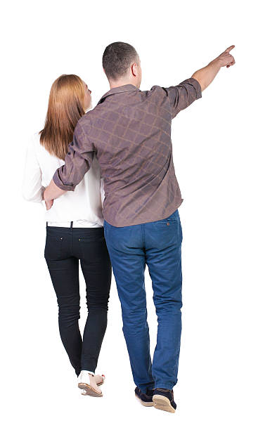 istock Back view of walking young couple (man and woman) pointing. 515633961