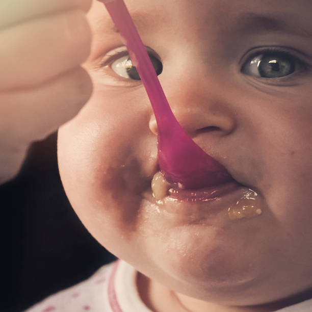 istock Feeding a baby girl with a spoon - messy 515646656