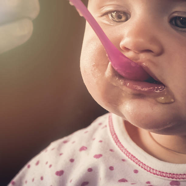 istock Feeding a baby girl with a spoon - messy 515657110
