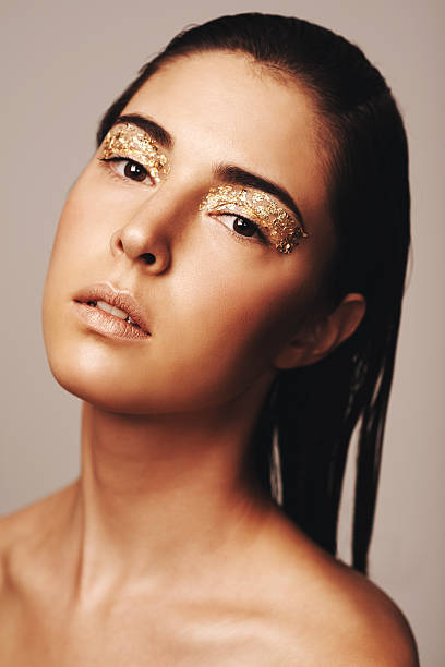 All that glitters Portrait of an attractive brunette with golden flakes around her eyes glitter makeup stock pictures, royalty-free photos & images