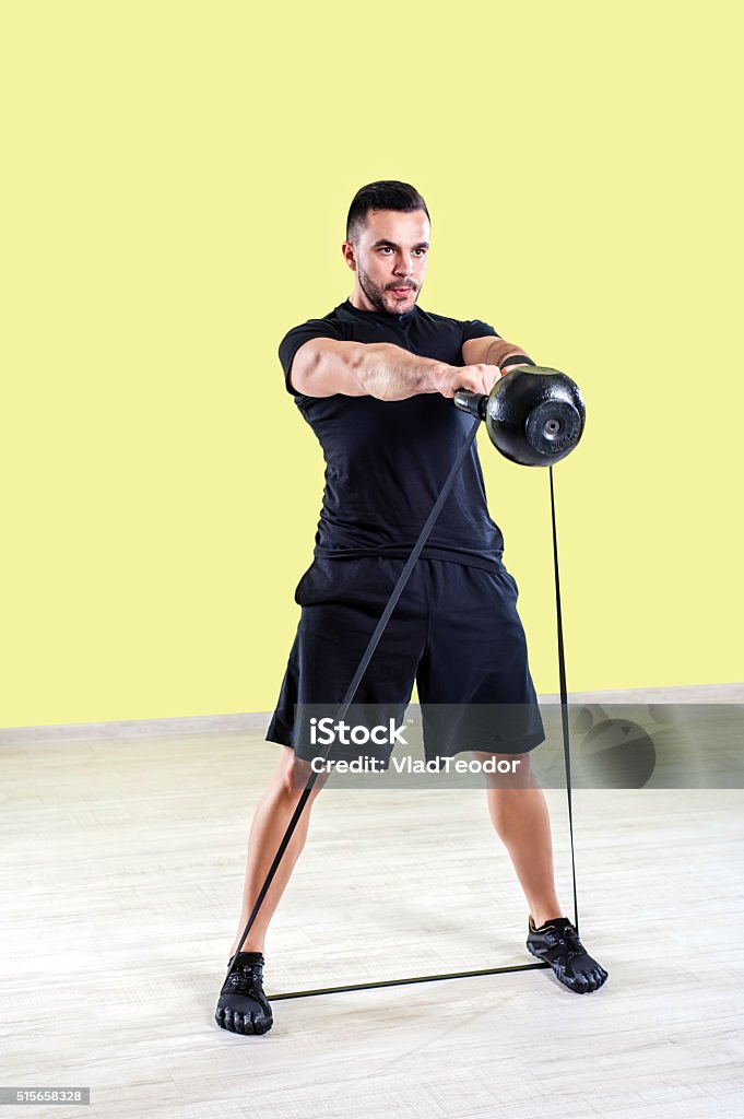 Man doing gym work out. Man Does gym Lift Ups With Fitness In The Gym's Studio with Kettle Bell and elastic band. Push-ups Stock Photo