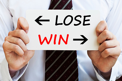Choosing lose or win. Businessman holding a paper with a motivational concept written on it.