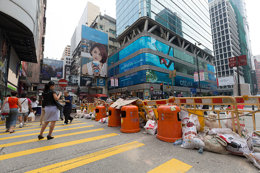 Hong Kong, Hong Kong SAR - September 30, 2014: Pedestrians at Mong Kok, Hong Kong. A street blocked by barricades and rubbish bins set up by protesters. Occupy Central is a civil disobedience movement which began in Hong Kong on September 28, 2014.