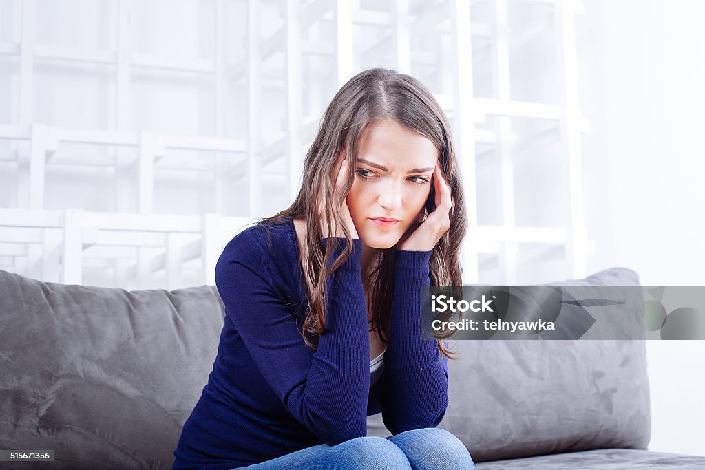 Young Woman Sitting On Sofa having headache migraine Young Woman Sitting On Sofa having headache migraine. Stress and depression. Adult Stock Photo