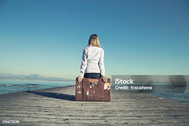 Woman Sitting On Her Suitcase Waiting For The Sunset Stock Photo - Download Image Now
