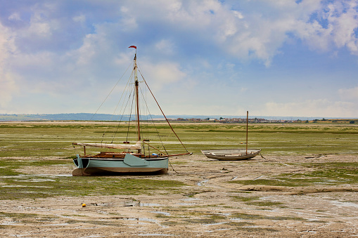 Traditional wooden sailing / fishing boats sitting on the estuary mud flats during low tide.