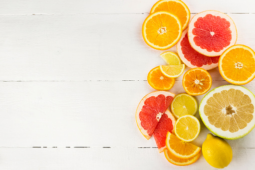 Various citrus on white wooden background