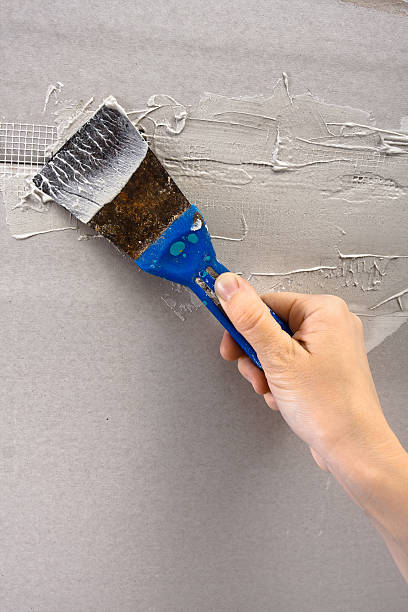 istock hand coating wall of plaster, closeup 515676150