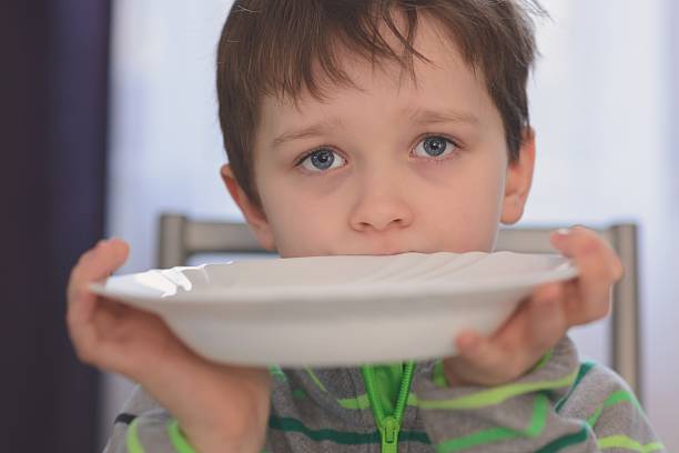 hambre niño con hermosos ojos espera para la cena. - hambriento fotografías e imágenes de stock