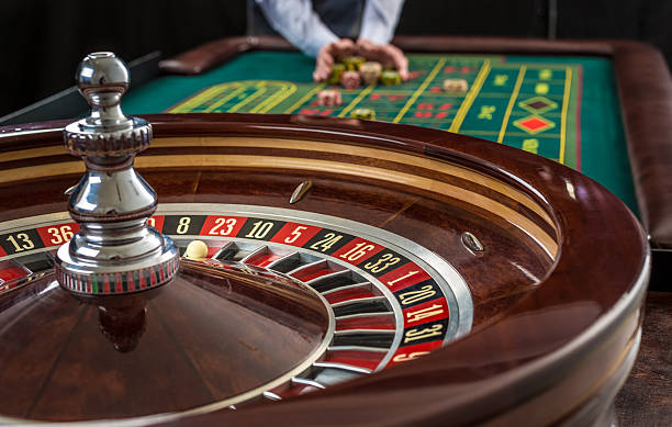 Roulette and piles of gambling chips on a green table. stock photo