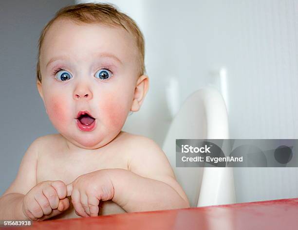 Surprised Kid Sitting At Table Stock Photo - Download Image Now - Baby - Human Age, Surprise, Child