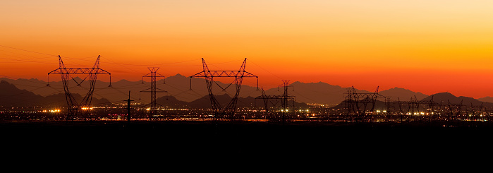 Power lines after sunset with city lights and mountains of Phoenix/Scottsdale Arizona in background.