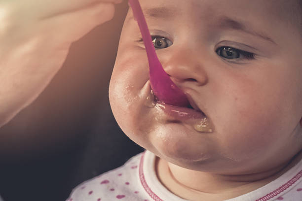 istock Feeding a baby girl with a spoon - messy 515684888